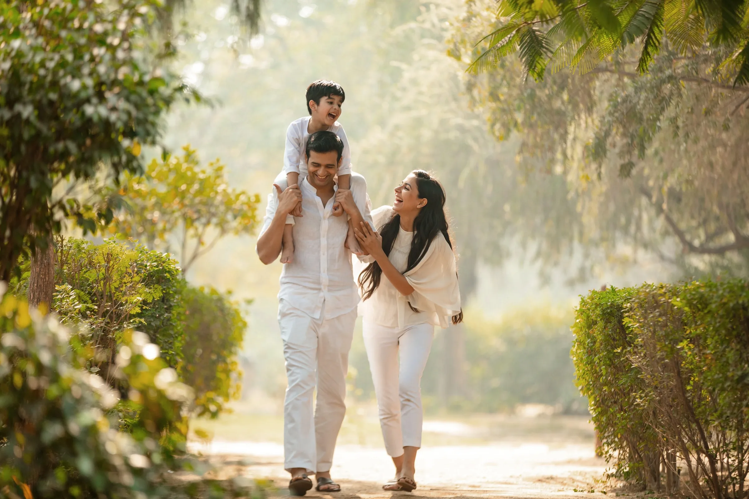 A family walking together along a green, tree-lined path